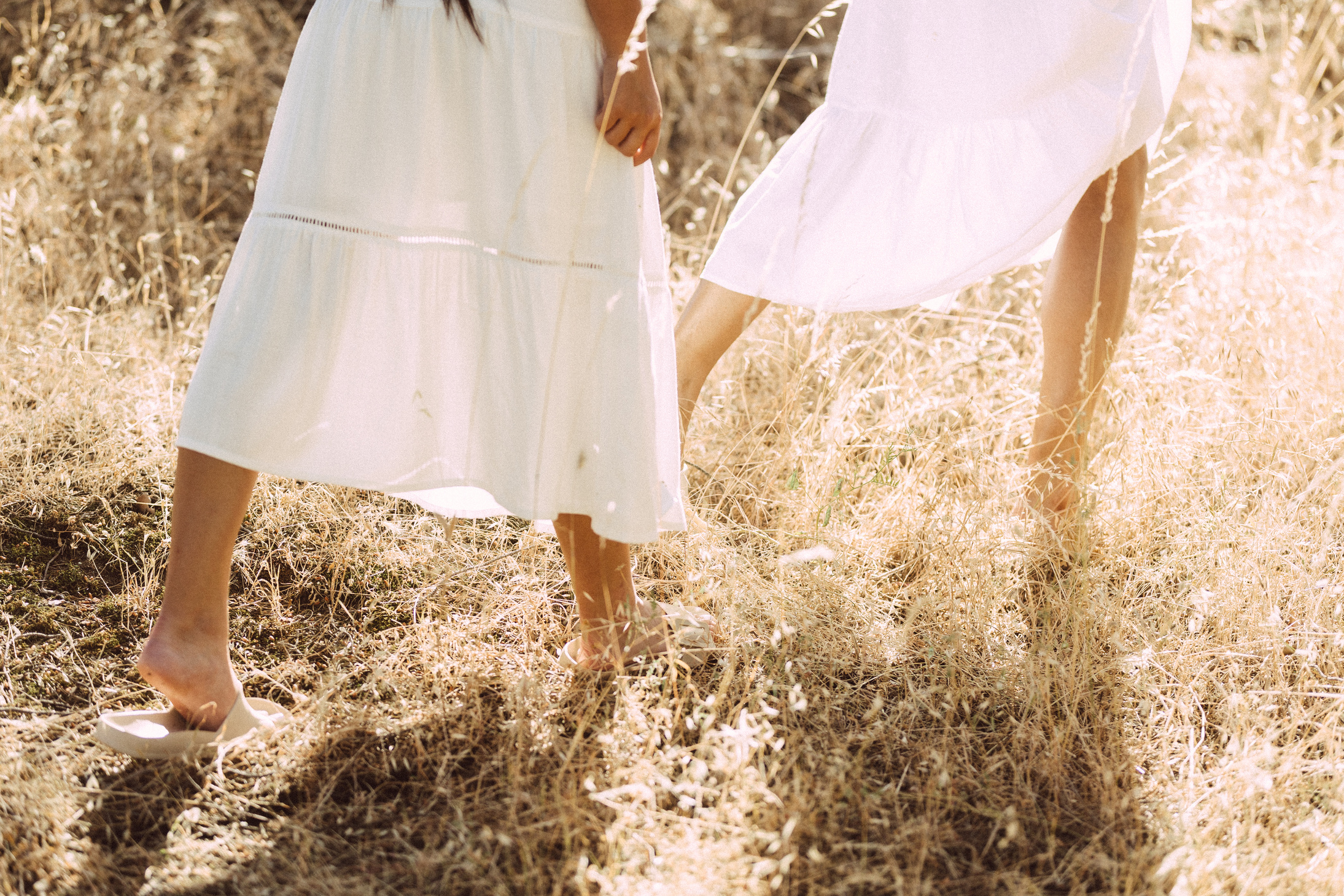 Two Women in Dresses Walking in the Field